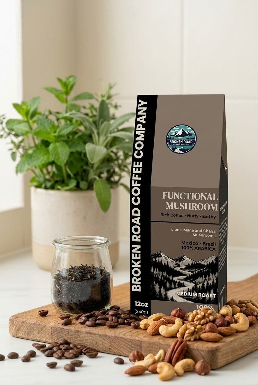 A bag of Brown Road Pumpkin Spice Ground Coffee stands on a wooden table beside a frosted glass mug filled with a latte, with coffee beans scattered around and small pumpkins in the background against a brick wall.