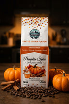 A bag of Golden Mountain Coffee Pumpkin Spice Ground Coffee stands on a wooden surface with coffee beans, cinnamon sticks, and small pumpkins around it. The package is white with orange and brown autumn-themed graphics and text.