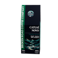 A 12oz package of Broken Road Coffee Company Catual Novo Medium Dark Roast coffee, featuring a dark navy blue box with green accents and a scenic mountain illustration.