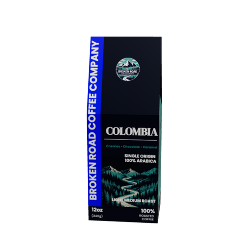 A 12oz package of Broken Road Coffee Company Colombia single-origin 100% Arabica coffee, featuring a dark blue and black design with a blue vertical banner on the left and a scenic mountain illustration.
